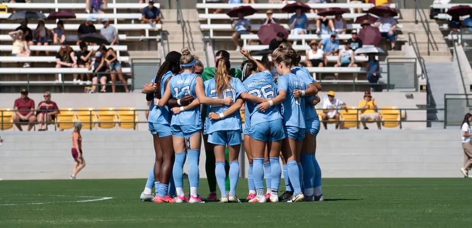 Equipo de fútbol femenino en círculo durante calentamiento