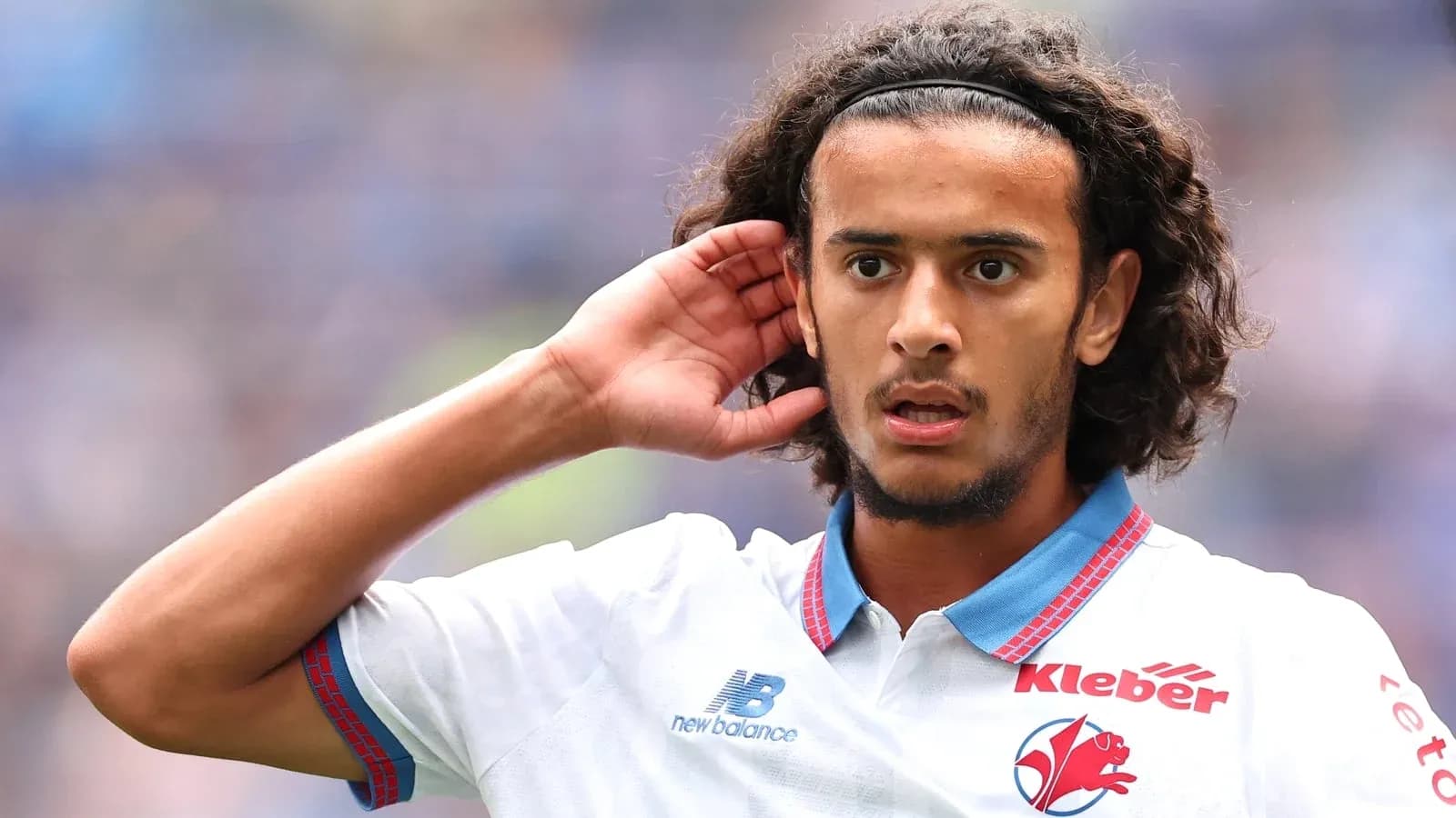 Jugador con camiseta blanca levantando la mano al oído