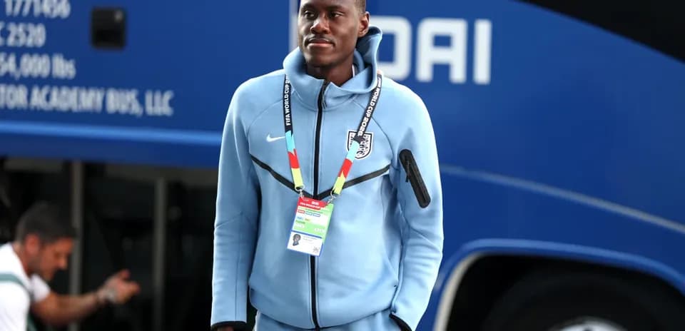 Jugador con uniforme azul cerca de autobús de equipo
