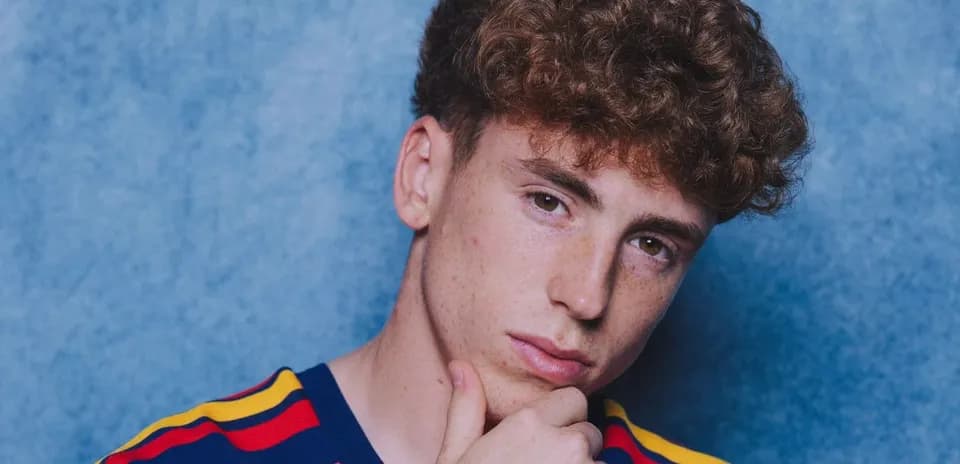 Joven posando con camiseta a rayas frente a fondo azul