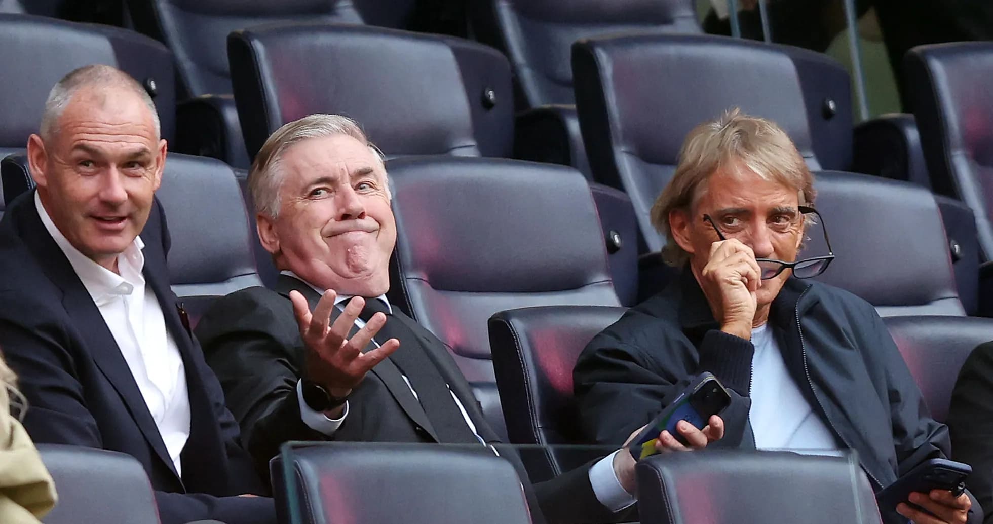 Tres hombres sentados en un estadio observando el partido
