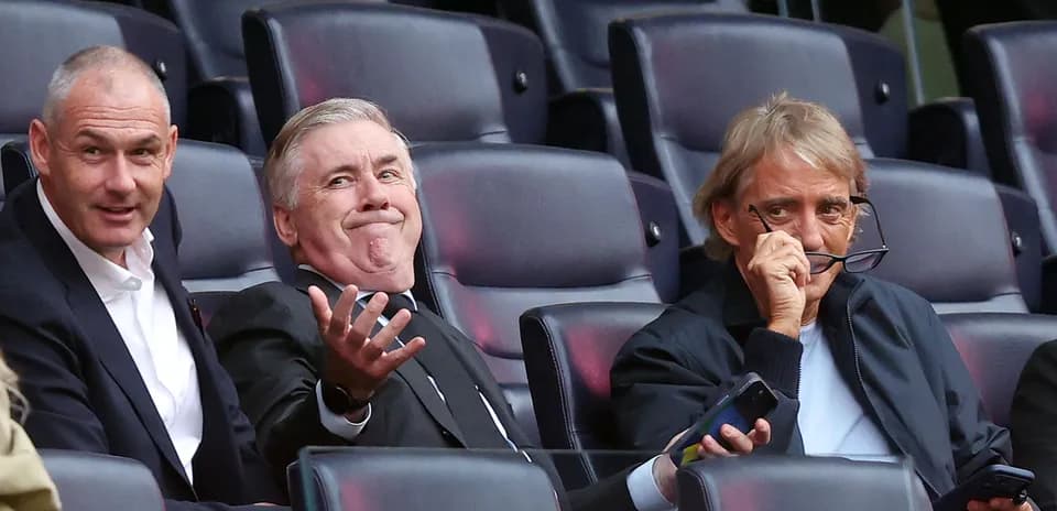 Tres hombres sentados en un estadio observando el partido