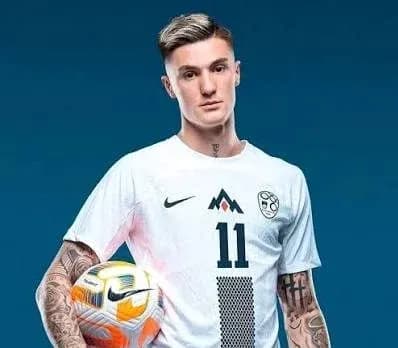 Jugador sosteniendo un balón de fútbol en uniforme