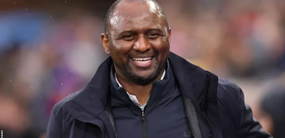 Entrenador sonriendo en el banquillo durante un partido