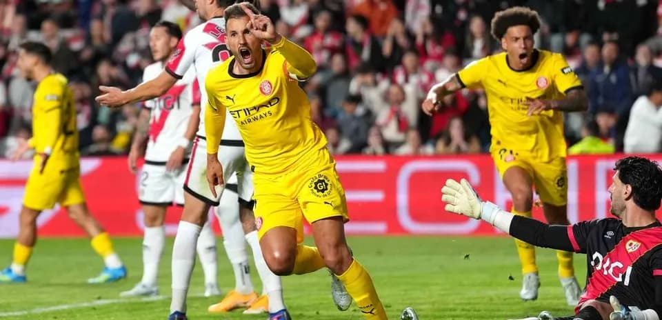 Jugador celebrando gol mientras el portero observa