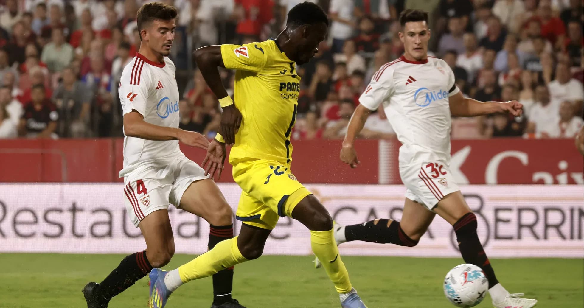 Jugador de Villarreal driblando a dos de Sevilla