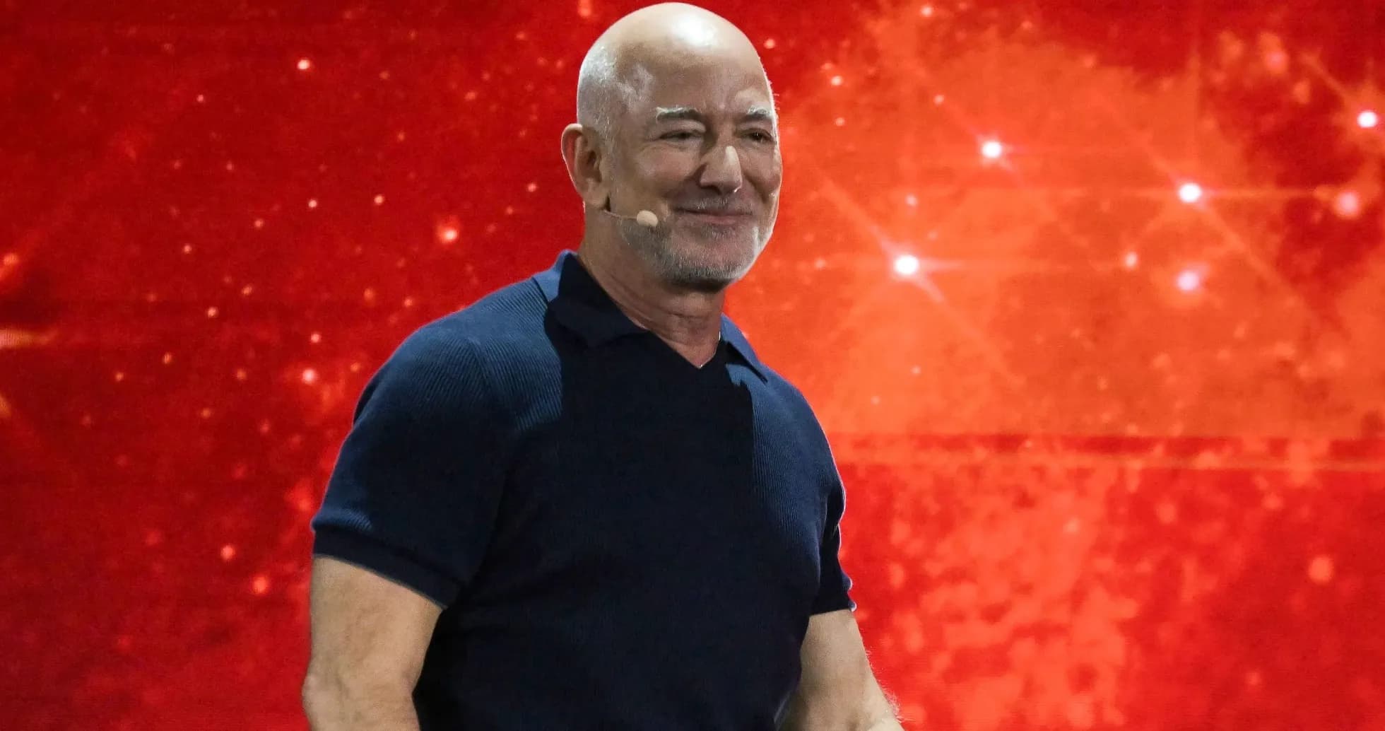 Hombre sonriendo en escenario con fondo rojo
