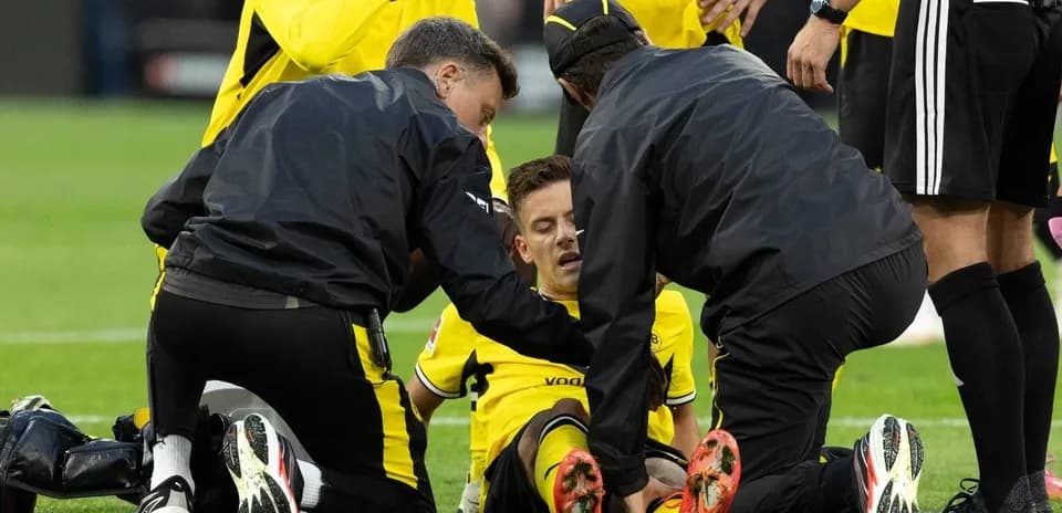 Jugadores de Dortmund atendiendo a un compañero lesionado