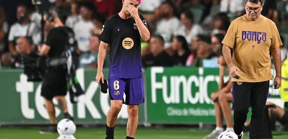 Jugador con cabello rosa camina cabizbajo en el campo