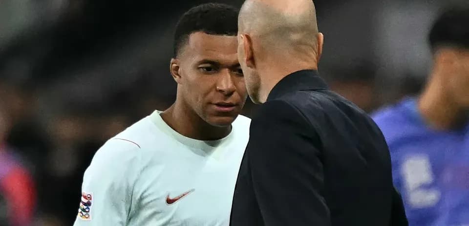 Kylian Mbappé conversando con un entrenador