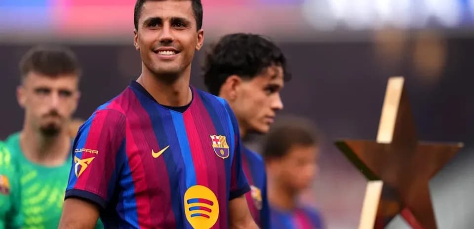 Jugador de Barcelona sonriendo con trofeo en campo
