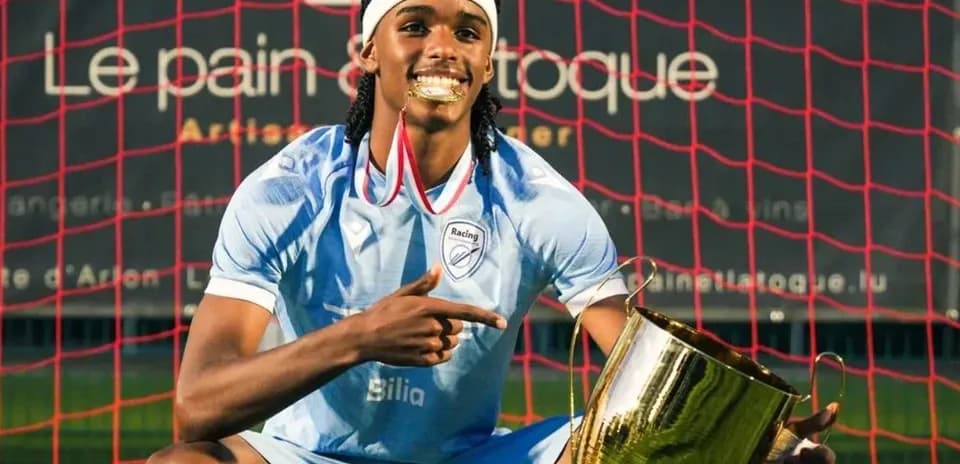 Jugador de Racing mostrando trofeo en el campo