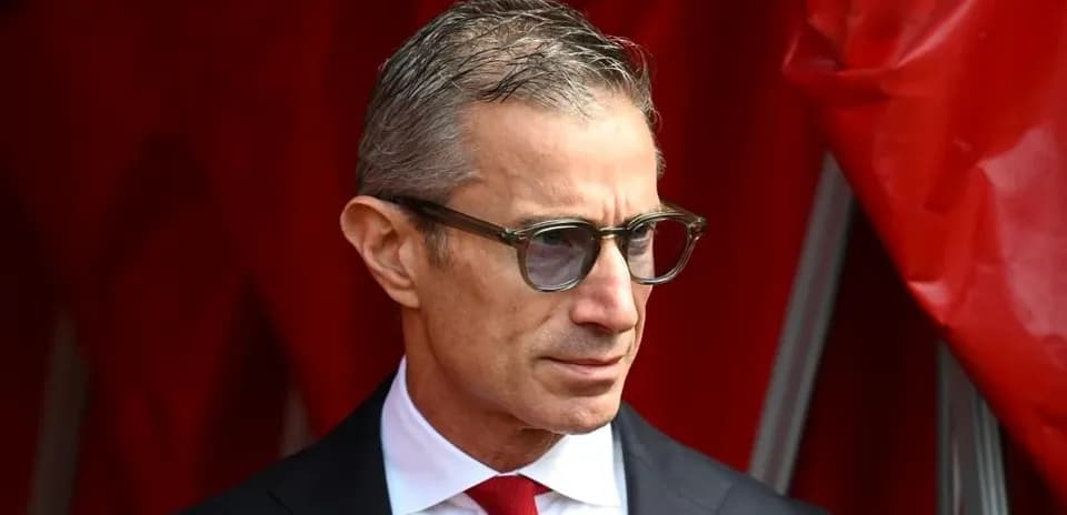 Persona con gafas y traje oscuro en fondo rojo