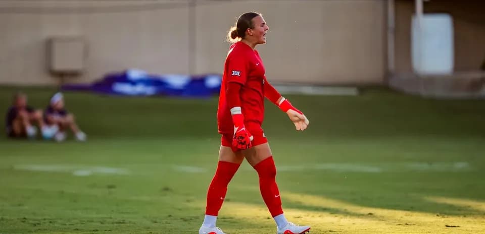 Portera en uniforme rojo caminando por el campo