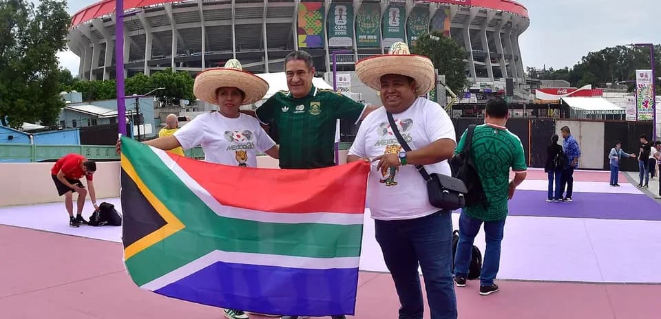 Tres aficionados sosteniendo una bandera de Sudáfrica