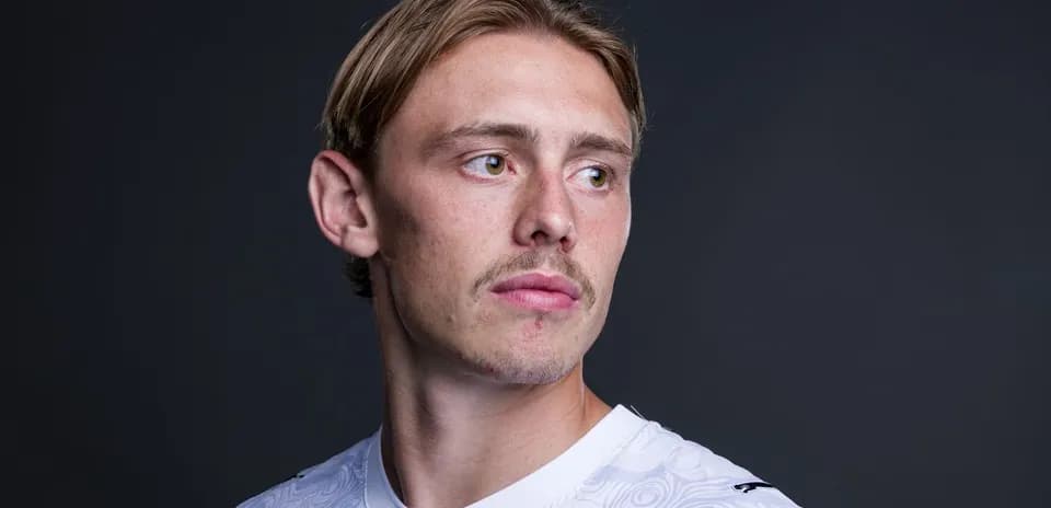 Jugador posando con camiseta blanca en fondo oscuro