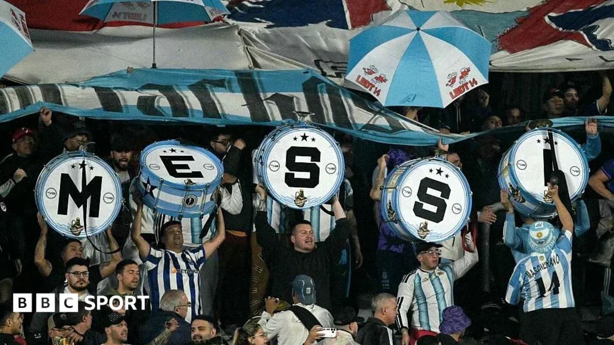 Aficionados sosteniendo tambores con letras en un estadio