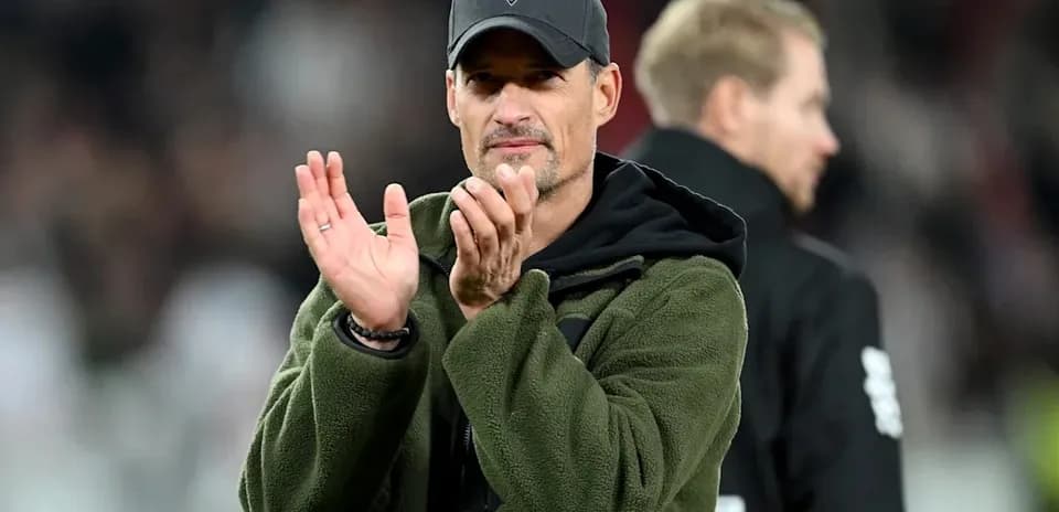 Entrenador aplaudiendo en el banquillo durante el partido