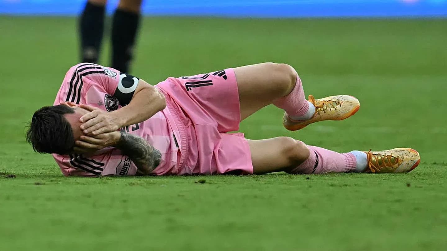 Jugador caído en el campo, sosteniendo su cabeza
