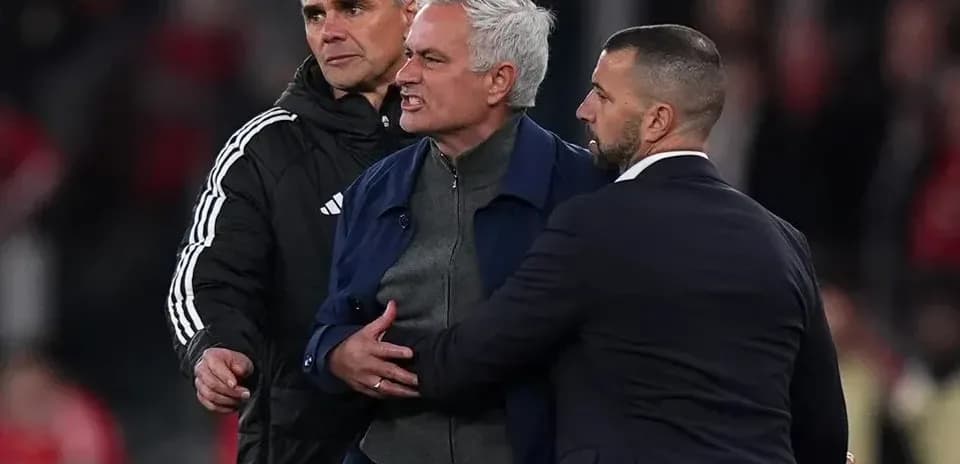 Entrenador siendo contenido por asistentes en el campo