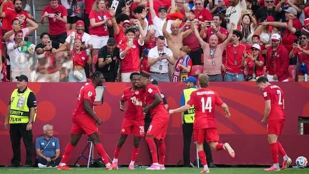 Jugadores celebrando un gol con aficionados animados