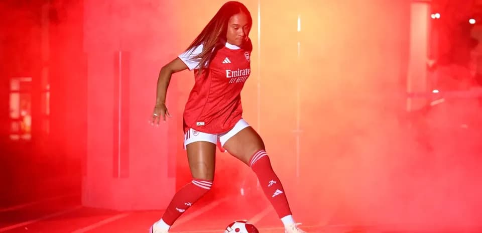 Jugadora de fútbol en uniforme de Arsenal con balón
