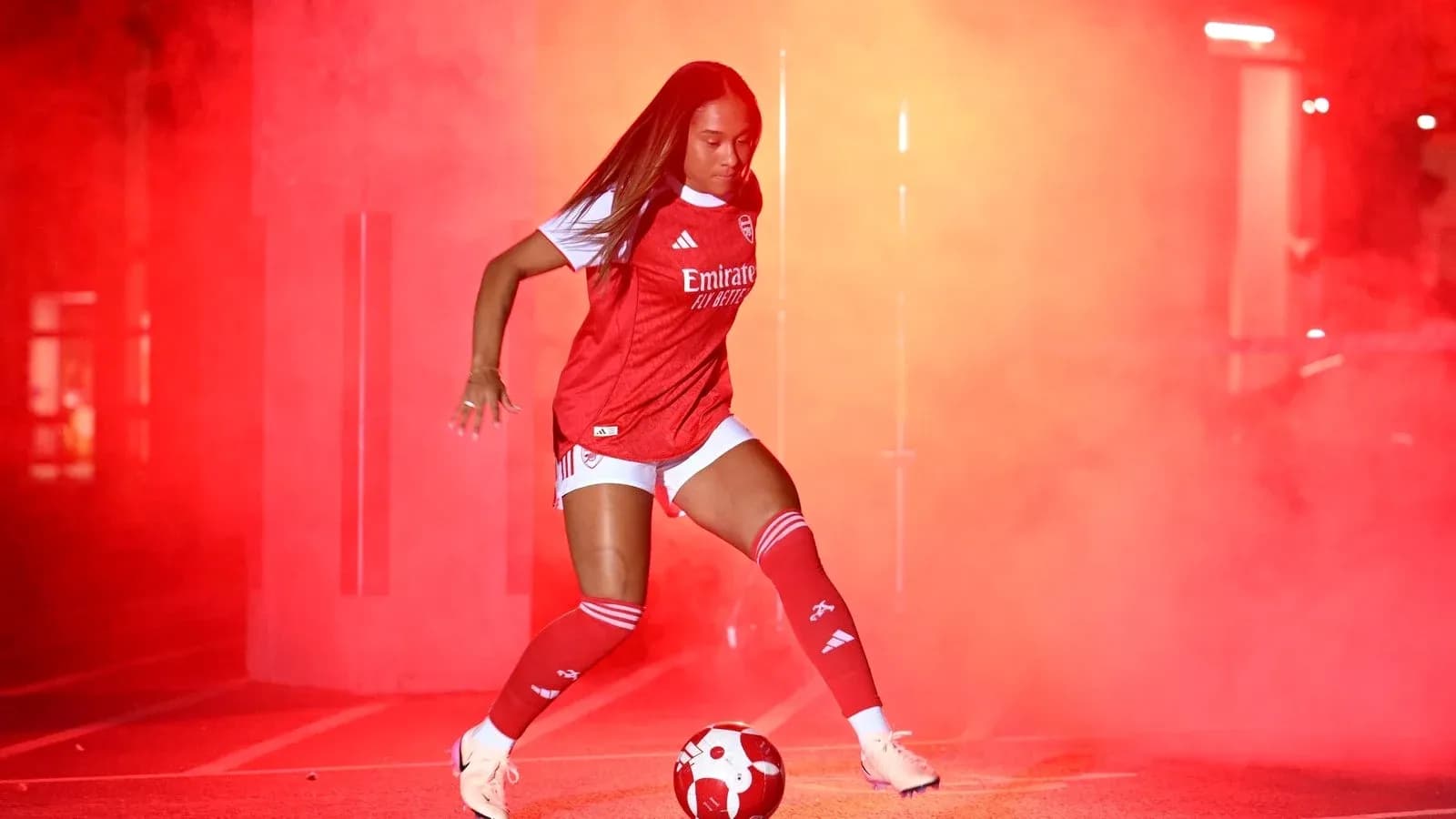 Jugadora de fútbol en uniforme de Arsenal con balón