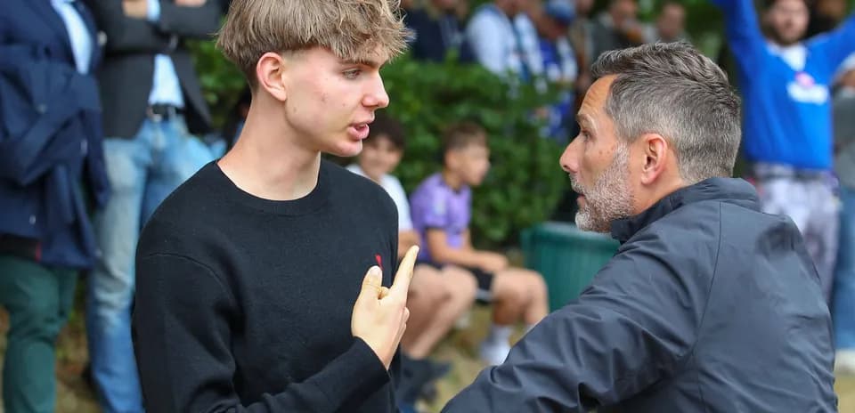 Dos hombres conversando intensamente en un evento deportivo