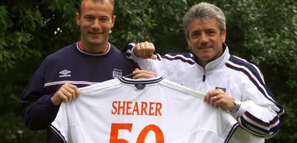 Dos personas sosteniendo camiseta con nombre 'SHEARER 50'