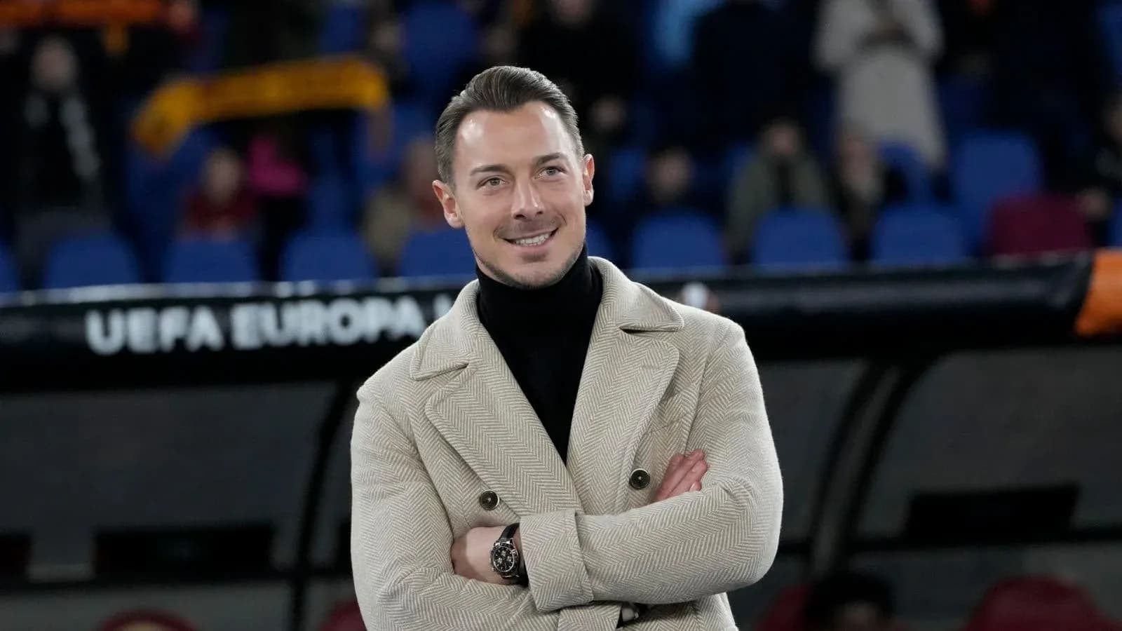 Hombre sonriendo en el banquillo del estadio