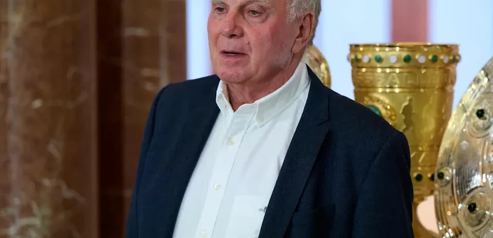 Hombre de pie junto a trofeos dorados