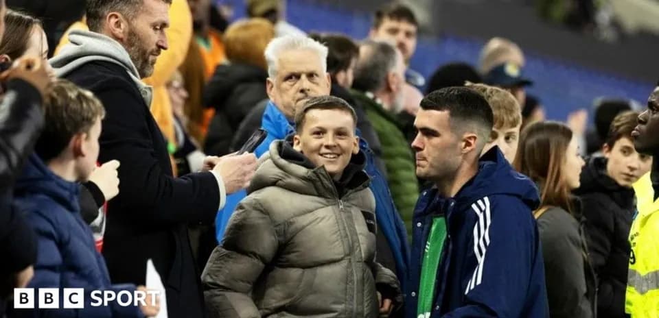 A boy smiling with a group of fans