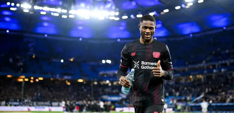 Jugador de fútbol sonriendo en el estadio con botella