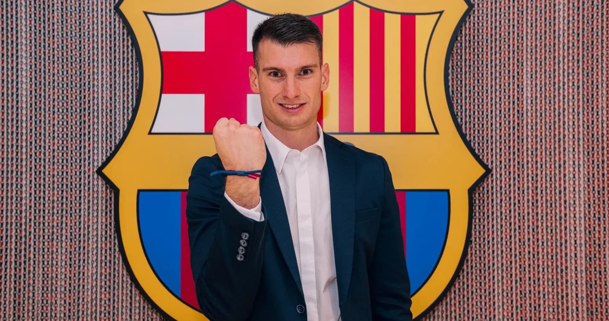 Jugador mostrando un puño frente al escudo del Barça