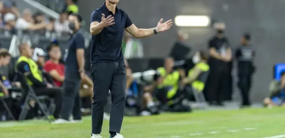 Entrenador gesticulando durante un partido de fútbol