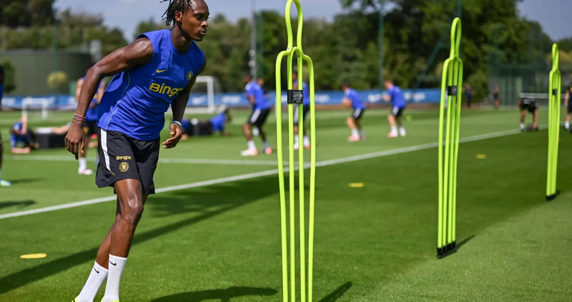 Jugador entrenando en campo con conos de entrenamiento