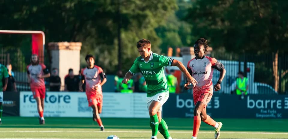 Jugador corriendo con el balón en partido de fútbol