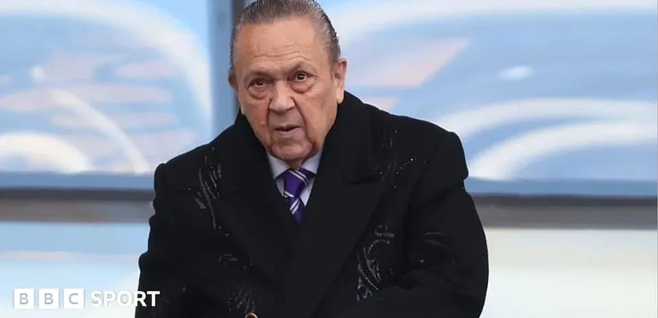 Hombre mayor con abrigo oscuro en evento deportivo