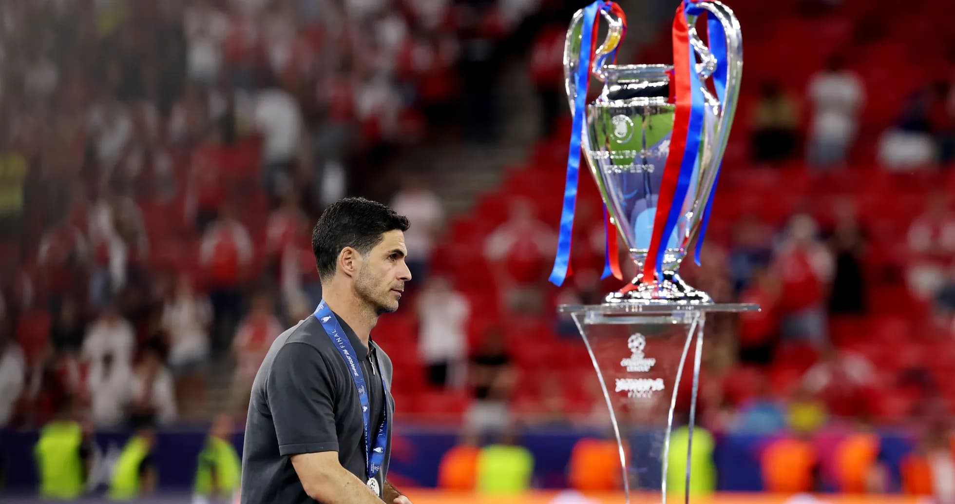 Entrenador caminando junto al trofeo de Champions League