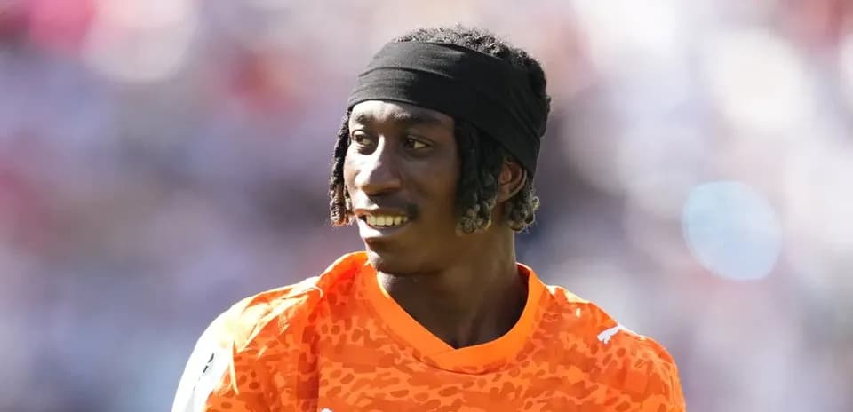 Jugador con camiseta naranja sonriendo en el campo