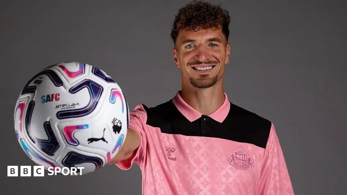 Jugador sosteniendo un balón de fútbol con sonrisa