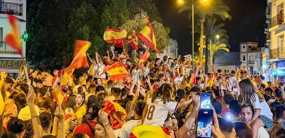 Multitud celebrando con banderas en la noche