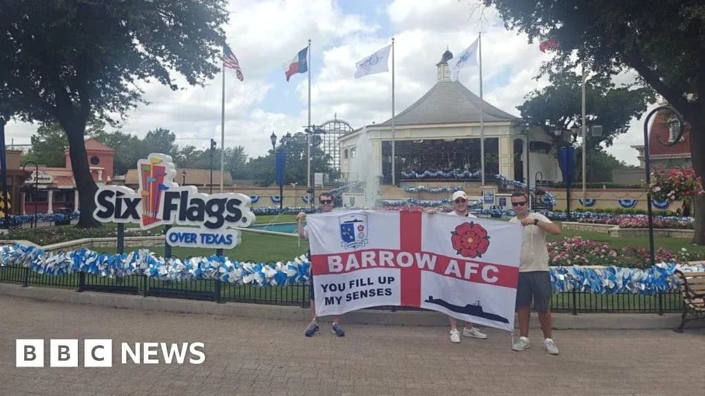 Dos aficionados sosteniendo una bandera de Barrow AFC
