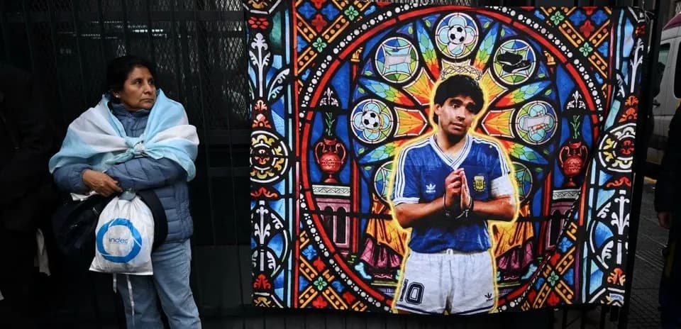 Mujer con bufanda argentina junto a mural de Maradona
