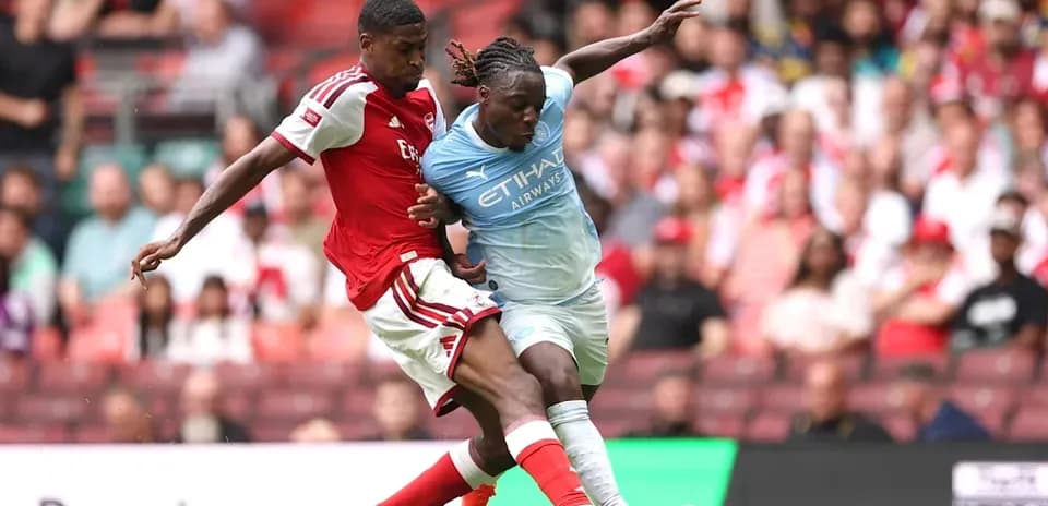 Jugador de Arsenal desafiando a jugador de Manchester City
