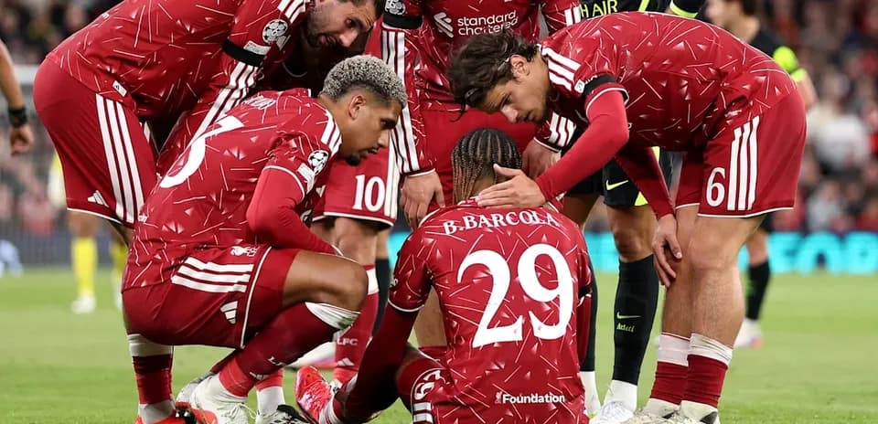 Jugadores de Liverpool apoyando a compañero en el suelo