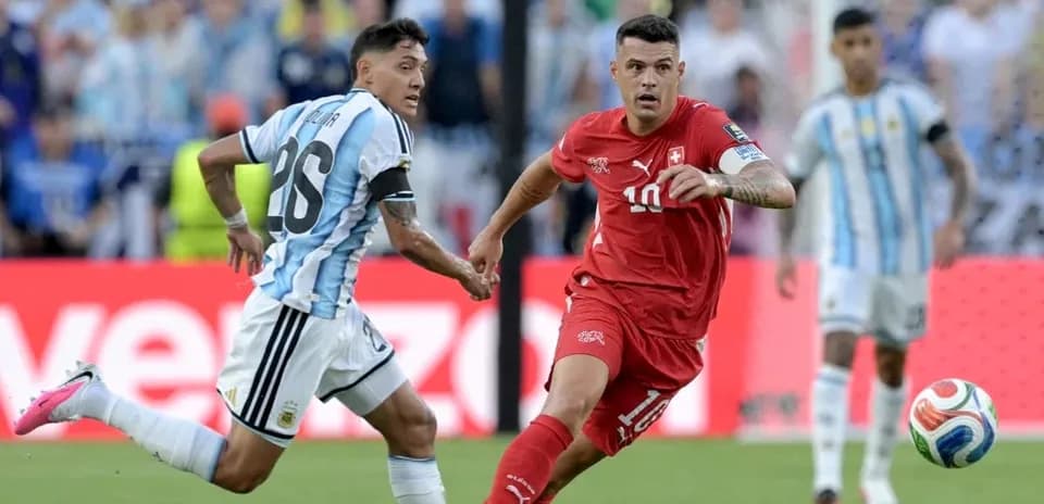 Jugador suizo driblando mientras es marcado por argentino