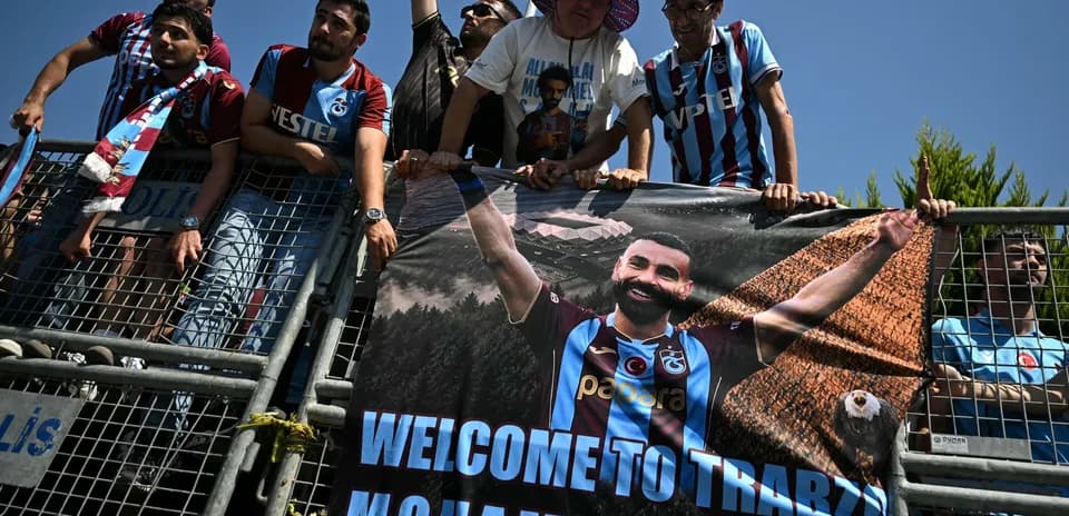 Aficionados sosteniendo un cartel de bienvenida en el estadio