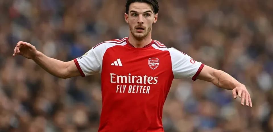 Jugador de Arsenal corriendo con el balón en el campo