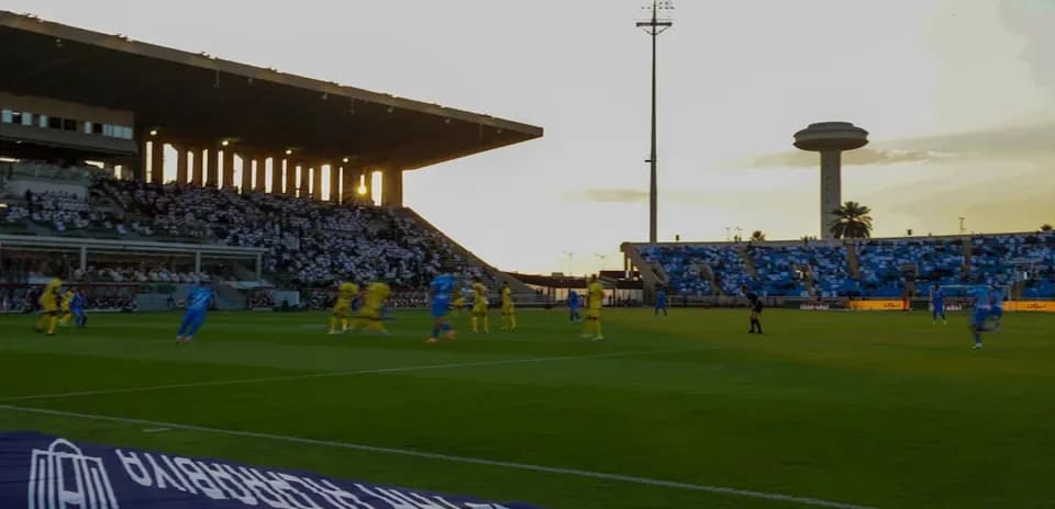 Partido de fútbol en estadio al atardecer